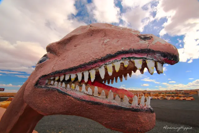A big roadside dinosaur sculpture with a mouthful of teeth