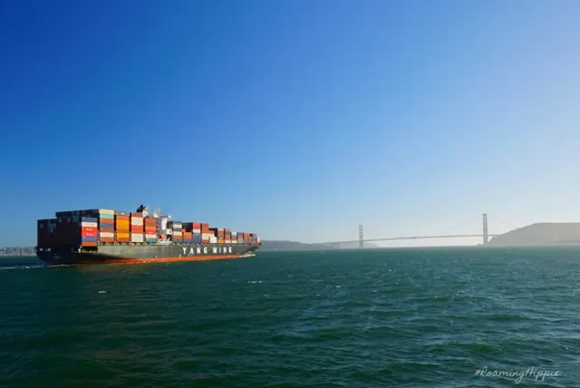 A loaded container ship sailing into San Francisco Bay with the Golden Gate Bridge far behind