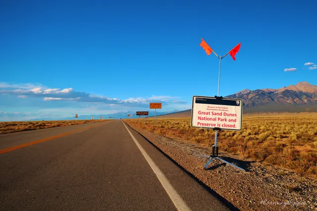 A long empty road heading toward snow-dusted mountains
