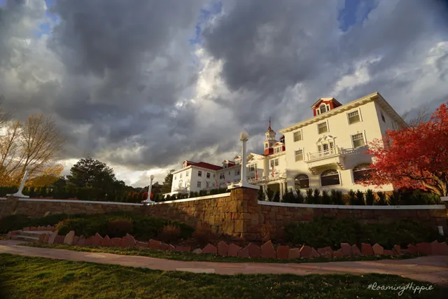 A white historic hotel under heavy grey clouds with red autumn trees