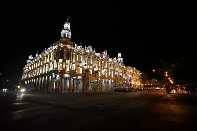 A grand historic theatre lit up at night in Havana
