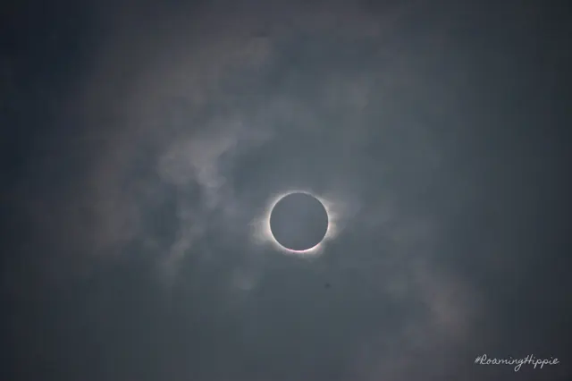 The total solar eclipse with a bright ring of light in a cloudy sky