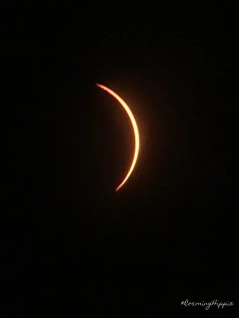 A curved orange crescent of the sun during the eclipse
