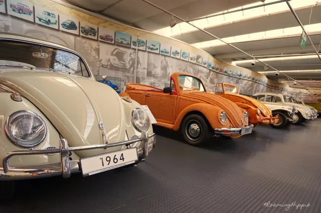 A row of classic Volkswagen Beetles, including a 1964 model