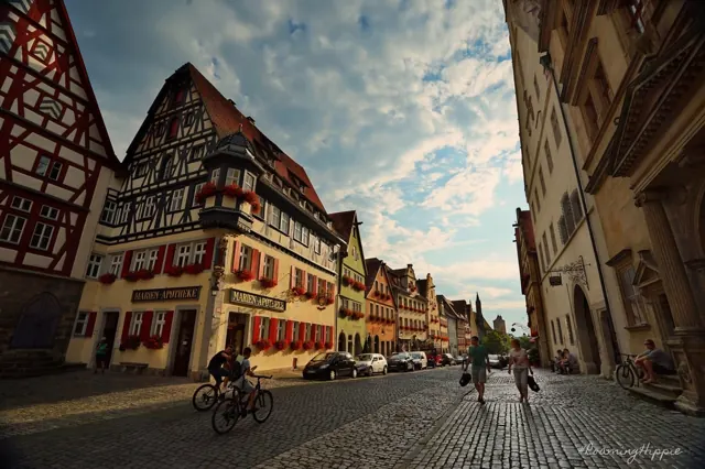A cyclist on a cobbled street lined with half-timbered houses