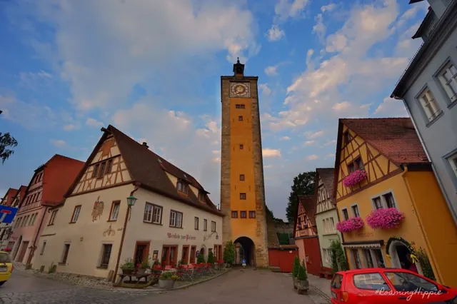 A tall clock tower above a cobbled square with flower boxes