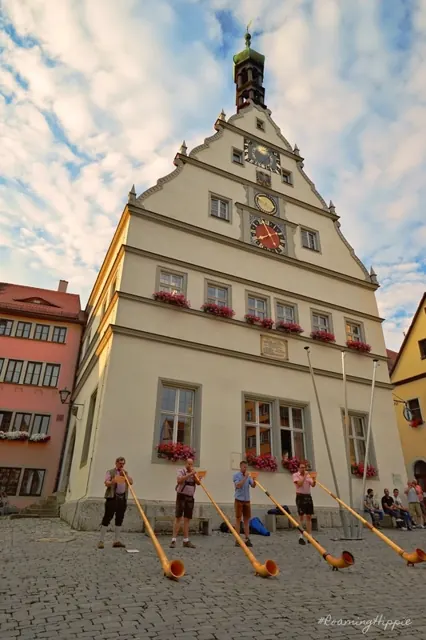 Alphorn players performing in front of an old council building