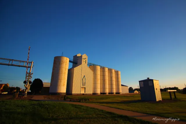 Rounded white grain silos and a railroad signal under a deep blue sky