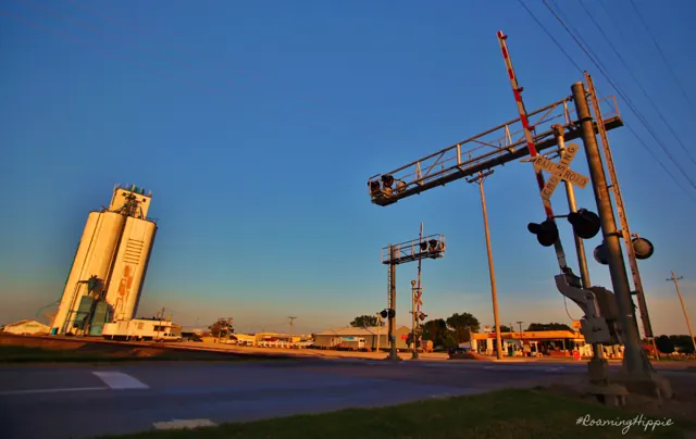 A grain elevator and railroad crossing signals at dusk