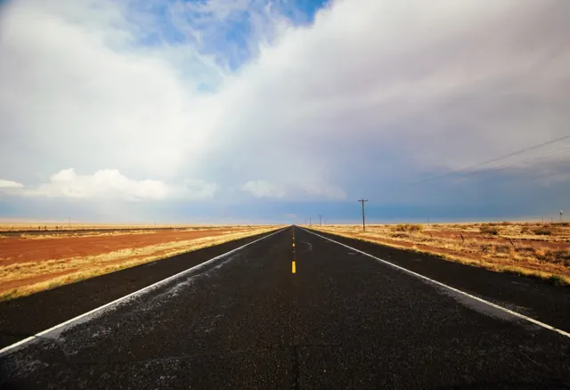 A straight desert highway heading toward distant rain clouds