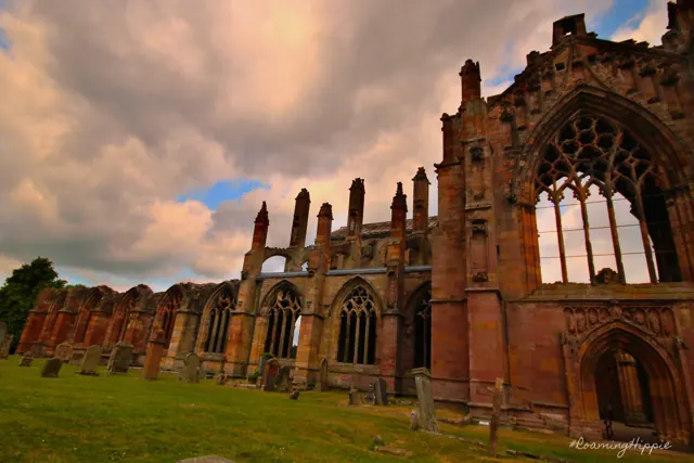 The long ruined nave of an abbey at sunset