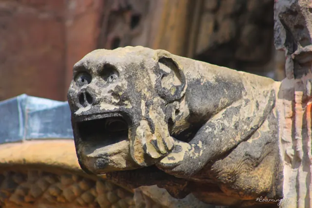 A weathered stone gargoyle with its mouth open