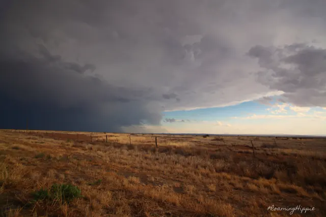 A dark storm front moving across a wide, empty plain