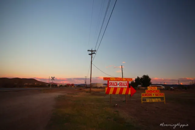 Bright roadside signs and power lines at dusk